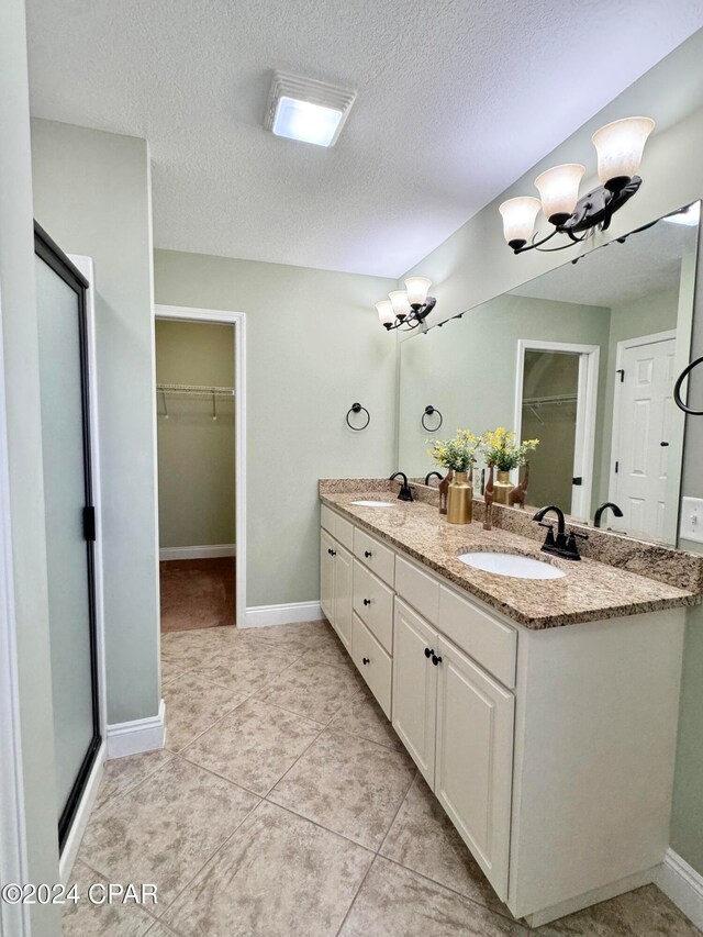 bathroom featuring vanity, an inviting chandelier, tile patterned flooring, walk in shower, and a textured ceiling