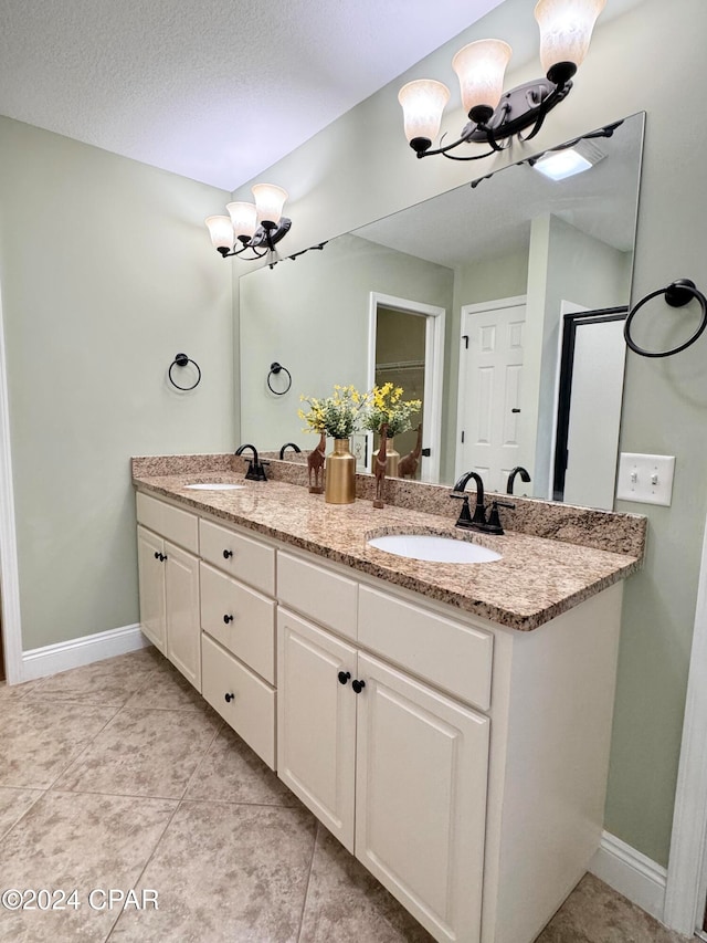 bathroom with tile patterned flooring, a textured ceiling, vanity, and a chandelier