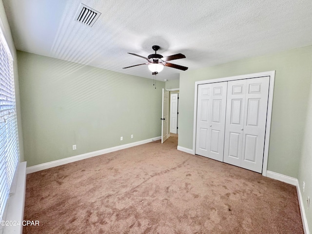 unfurnished bedroom featuring ceiling fan, a closet, carpet floors, and a textured ceiling