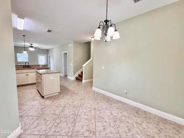 kitchen with sink, hanging light fixtures, light tile patterned floors, a kitchen island, and ceiling fan with notable chandelier