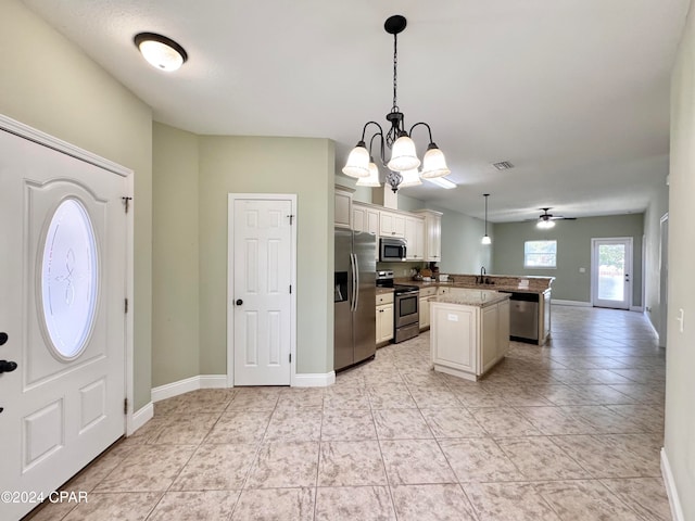 kitchen featuring a center island, sink, stainless steel appliances, pendant lighting, and ceiling fan with notable chandelier