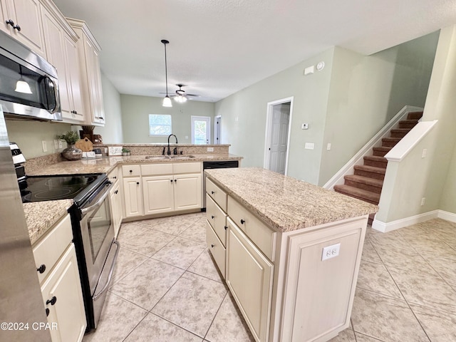 kitchen with sink, stainless steel appliances, kitchen peninsula, pendant lighting, and a kitchen island