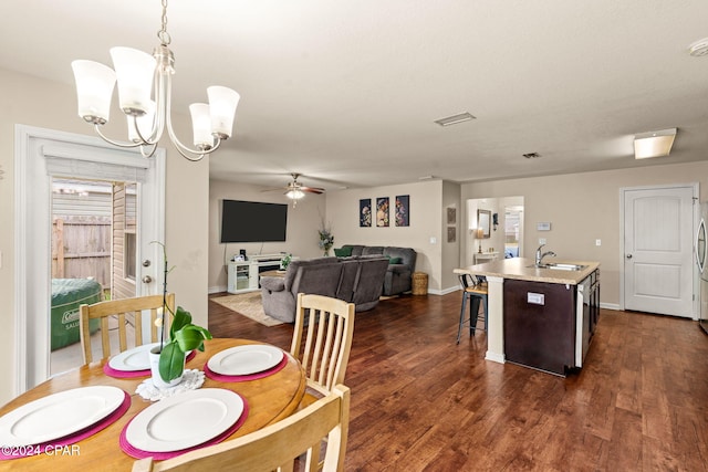 dining area featuring ceiling fan with notable chandelier, dark hardwood / wood-style flooring, and sink