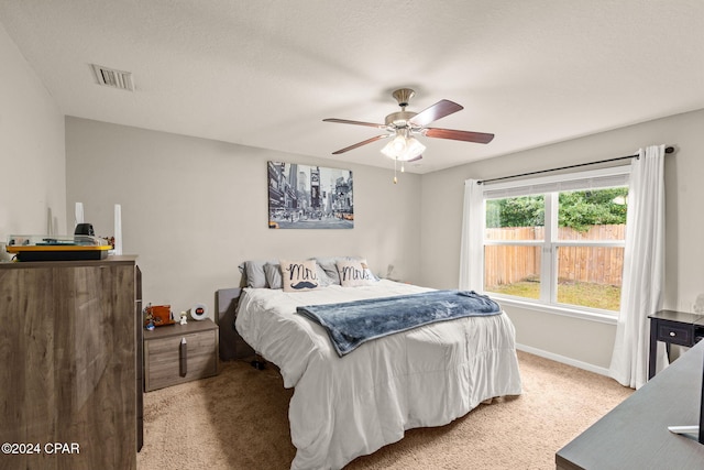 carpeted bedroom featuring ceiling fan and a textured ceiling