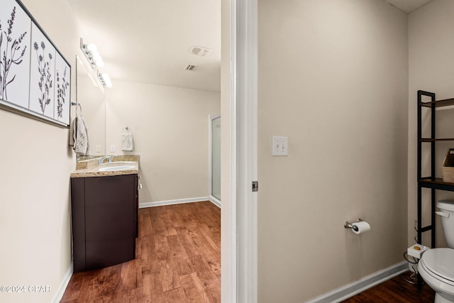 bathroom featuring walk in shower, hardwood / wood-style floors, vanity, and toilet