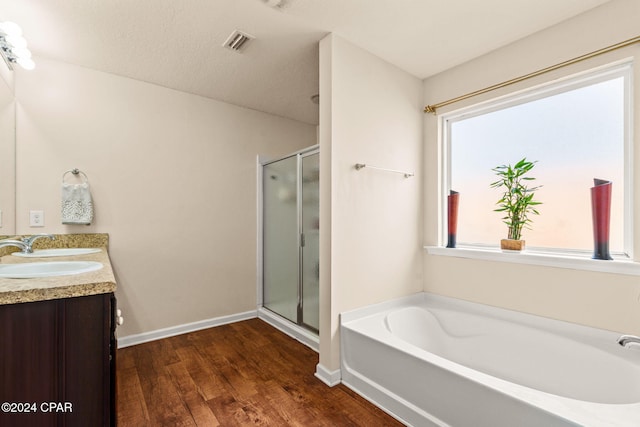 bathroom featuring independent shower and bath, vanity, wood-type flooring, and a textured ceiling