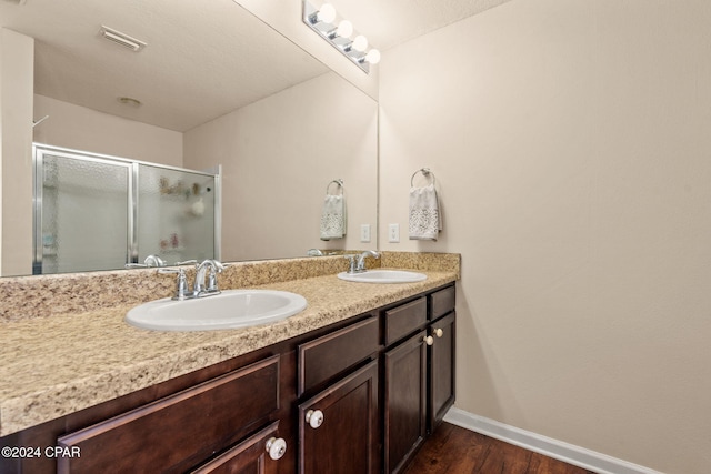 bathroom with hardwood / wood-style floors, vanity, and an enclosed shower