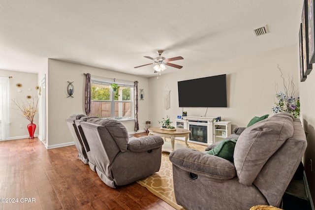 living room featuring ceiling fan, hardwood / wood-style floors, and a textured ceiling