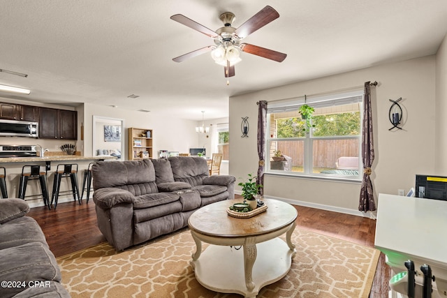 living room featuring hardwood / wood-style floors, ceiling fan with notable chandelier, and a textured ceiling