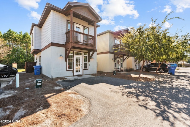 view of front of house with a balcony and french doors