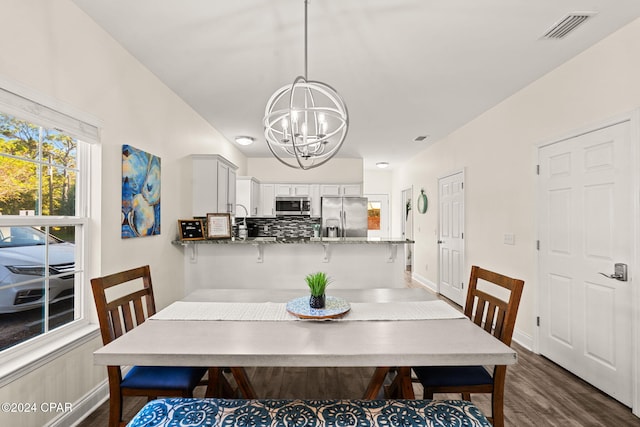 dining space with an inviting chandelier and dark hardwood / wood-style flooring