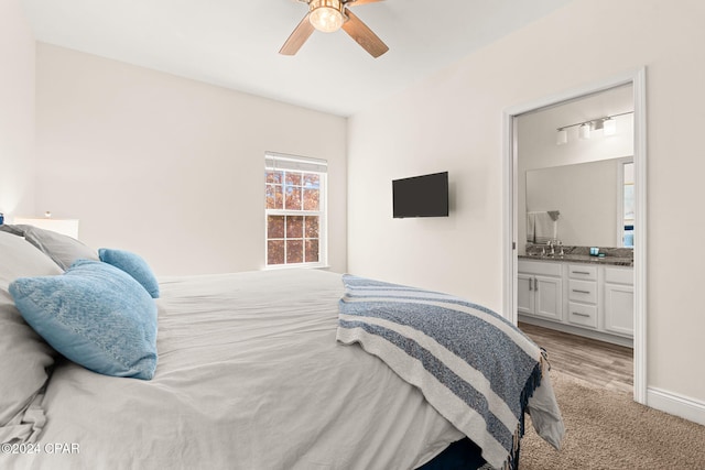 bedroom featuring ceiling fan, ensuite bathroom, and light wood-type flooring