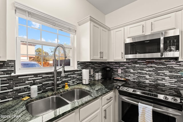 kitchen featuring white cabinetry, tasteful backsplash, stainless steel appliances, and dark stone counters