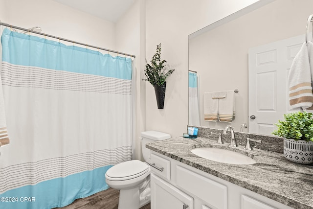 bathroom featuring toilet, hardwood / wood-style floors, walk in shower, and vanity