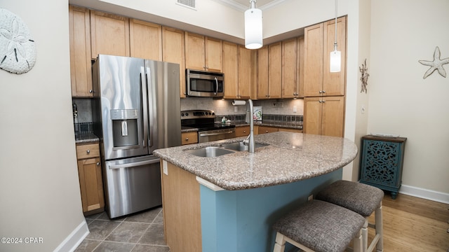 kitchen featuring decorative backsplash, ornamental molding, stainless steel appliances, decorative light fixtures, and a center island with sink