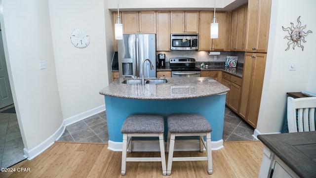 kitchen featuring pendant lighting, light hardwood / wood-style flooring, stainless steel appliances, and sink