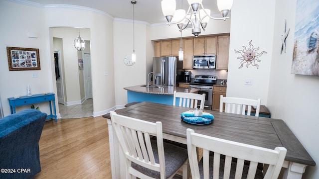 dining space featuring light hardwood / wood-style floors, ornamental molding, and sink