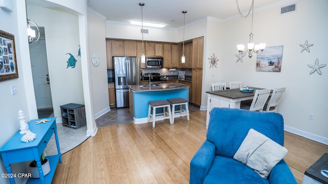 kitchen featuring ornamental molding, a center island, stainless steel appliances, and light hardwood / wood-style flooring