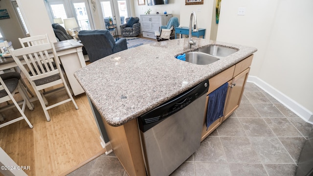 kitchen featuring sink, light stone counters, stainless steel dishwasher, a kitchen island with sink, and light tile patterned flooring