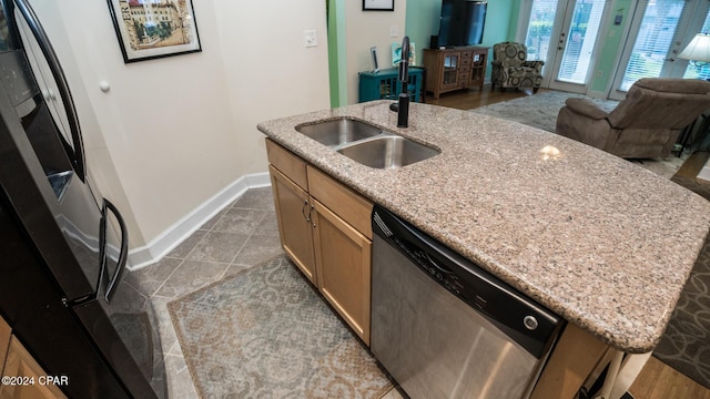 kitchen featuring a sink, open floor plan, freestanding refrigerator, dishwasher, and a center island with sink