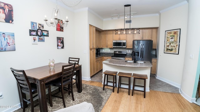 kitchen featuring stainless steel appliances, pendant lighting, a kitchen island, and ornamental molding