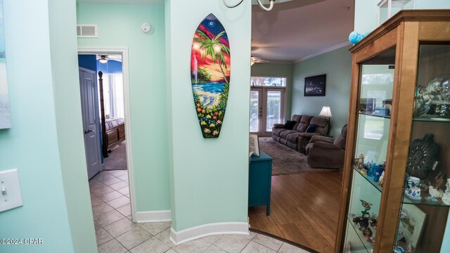 hallway featuring french doors, ornamental molding, and light tile patterned floors