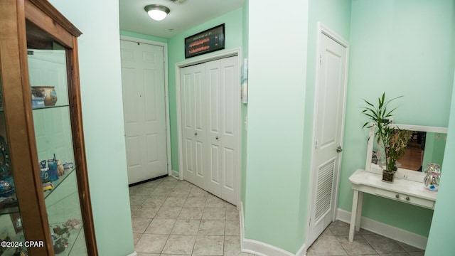 hall featuring visible vents, baseboards, and light tile patterned floors