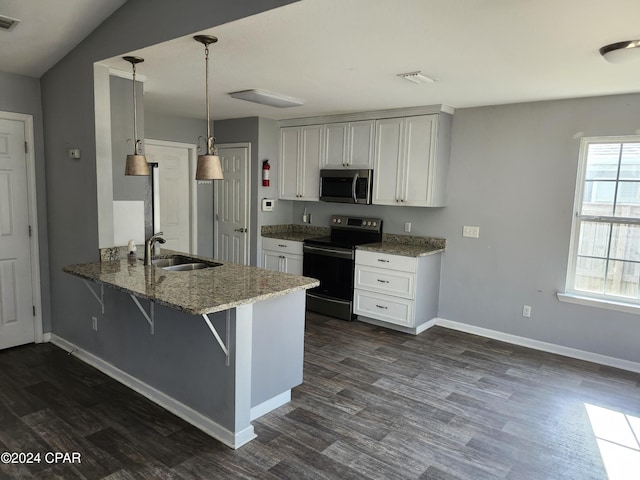 kitchen featuring sink, a breakfast bar, appliances with stainless steel finishes, decorative light fixtures, and kitchen peninsula