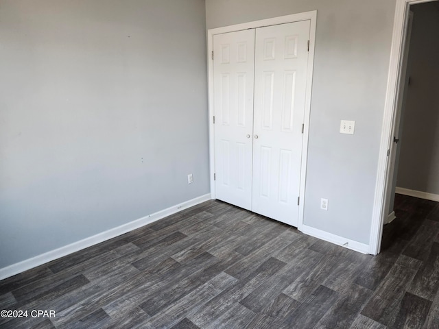 unfurnished bedroom with a closet and dark wood-type flooring