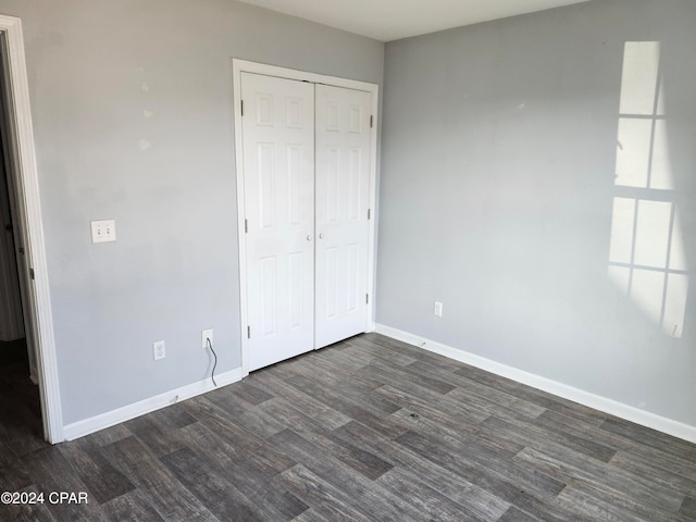 unfurnished bedroom with dark wood-type flooring and a closet