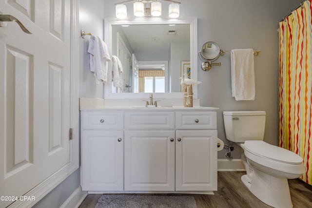 bathroom featuring wood-type flooring, vanity, toilet, and walk in shower