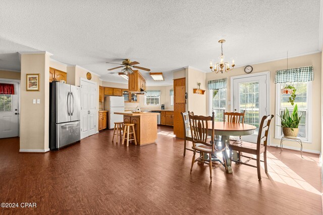 dining space with ceiling fan with notable chandelier, dark hardwood / wood-style floors, and crown molding