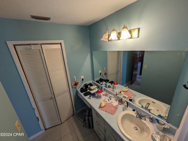 bathroom with tile patterned flooring, vanity, and a textured ceiling