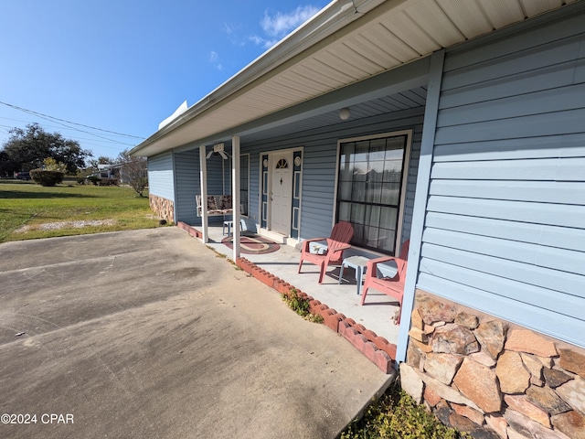 entrance to property with covered porch and a lawn