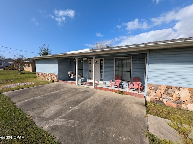 ranch-style house featuring covered porch and a front lawn