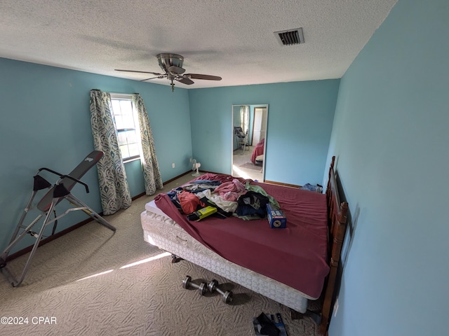 carpeted bedroom featuring ceiling fan and a textured ceiling