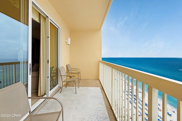 balcony featuring a view of the beach and a water view