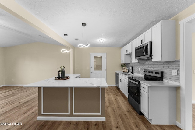 kitchen featuring white cabinetry, hanging light fixtures, light stone counters, appliances with stainless steel finishes, and light wood-type flooring