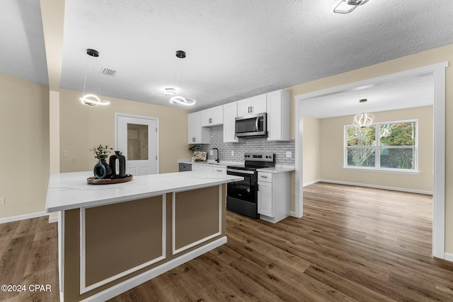 kitchen with light stone counters, stainless steel appliances, dark wood-type flooring, white cabinetry, and hanging light fixtures