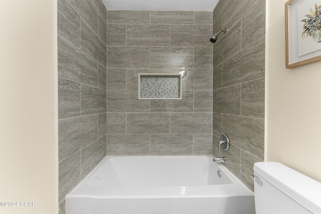 bathroom with tiled shower / bath combo and toilet