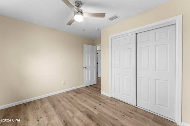 unfurnished bedroom featuring ceiling fan, light wood-type flooring, and a closet