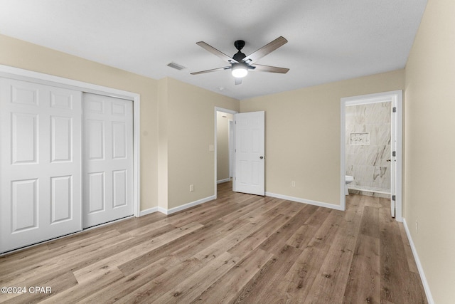 unfurnished bedroom with ensuite bathroom, ceiling fan, light wood-type flooring, and a closet