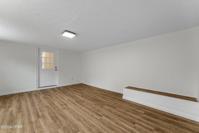 unfurnished room with wood-type flooring and a textured ceiling