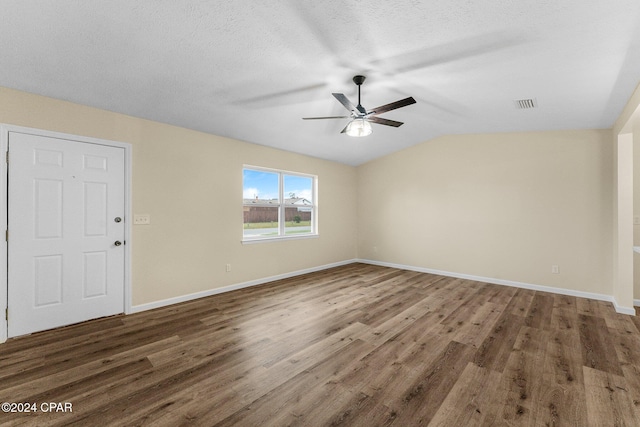 empty room featuring a textured ceiling, dark hardwood / wood-style floors, and lofted ceiling