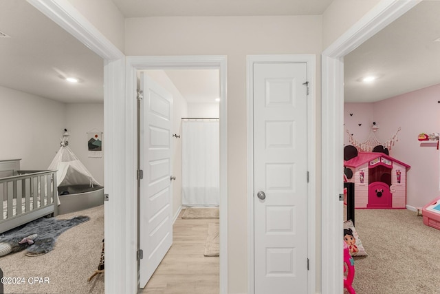 carpeted bedroom featuring a nursery area