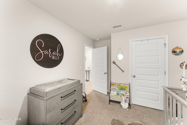 carpeted bedroom featuring a nursery area