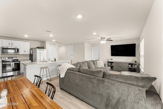 living room featuring light wood-type flooring and ceiling fan