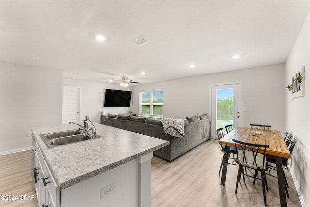 kitchen featuring a kitchen island with sink, sink, light hardwood / wood-style flooring, ceiling fan, and white cabinetry