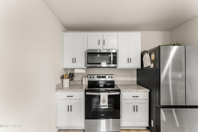 kitchen featuring white cabinets, stainless steel appliances, light hardwood / wood-style flooring, and light stone countertops