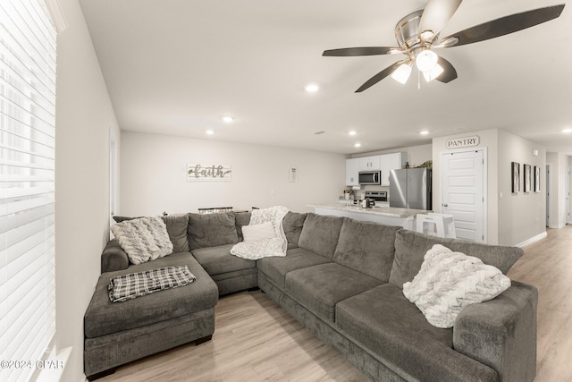 living room featuring light wood-type flooring and ceiling fan